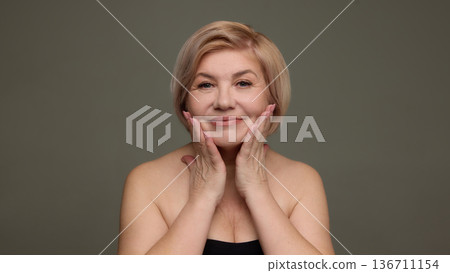 Mature woman holding face anti aging skincare portrait. 136711154