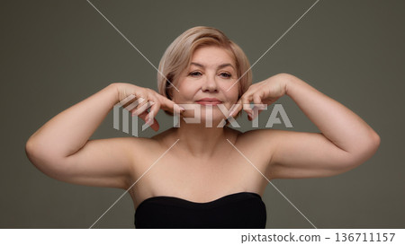 Mature woman pointing at jawline anti aging skincare. Mature woman pointing at jawline anti aging skincare. 136711157