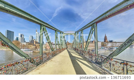 Iron footbridge with Frankfurt skyline over river Main Iron footbridge with Frankfurt skyline over river Main 136711693