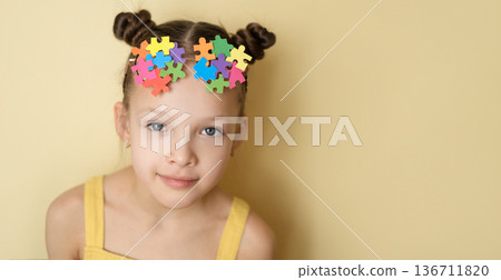 A beautiful girl with glasses on head, decorated with pieces of multicolored puzzles reflecting many different forms and manifestations of autism A beautiful girl with glasses on head, decorated with pieces of multicolored puzzles reflecting many different forms and manifestations of autism 136711820