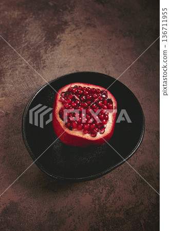 sliced fresh pomegranate, on a black plate, top view, rustic style, no people, 136711955
