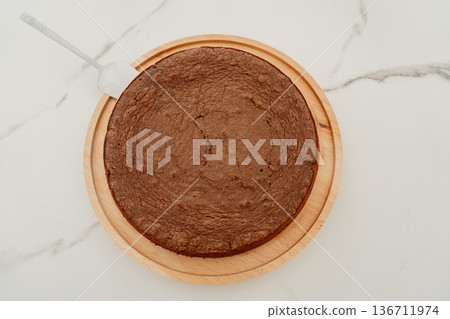 Top view of homemade chocolate cake on neutral background. Minimal flat lay composition perfect for baking blogs, recipe websites and culinary magazine layouts. Top view of homemade chocolate cake on neutral background. Minimal flat lay composition perfect for baking blogs, recipe websites and culinary magazine layouts. 136711974