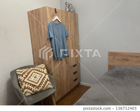 a T-shirt on a hanger in a closet in a hotel room a T-shirt on a hanger in a closet in a hotel room 136712403