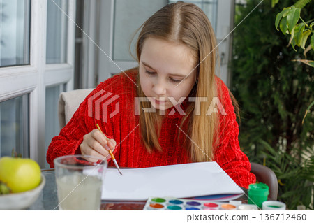 Cheerful child drawing pink cats in a sketchbook. Young preteen girl painting 136712460