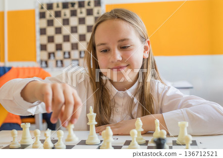 Beautiful child school student on chess lesson indoor. Young girl 10 years old playing chess 136712521