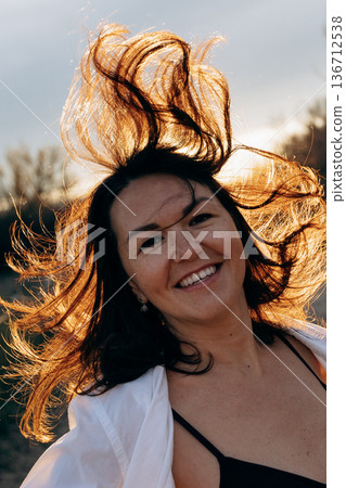 Cheerful Woman with Wind-Swept Hair Outdoors 136712538