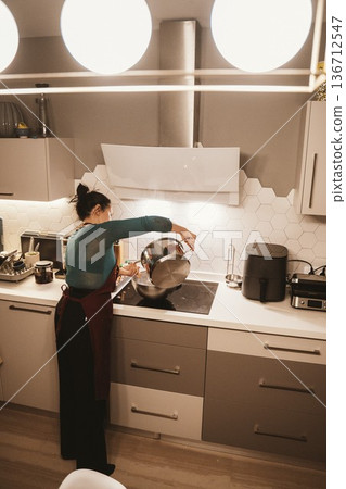 Woman Cooking in Modern Kitchen Pouring Ingredients Woman Cooking in Modern Kitchen Pouring Ingredients 136712547