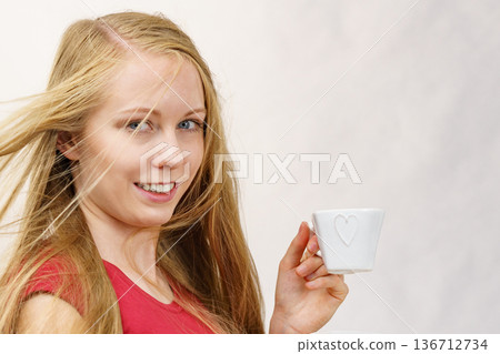 Blonde girl blowing hair holds coffee cup Blonde girl blowing hair holds coffee cup 136712734