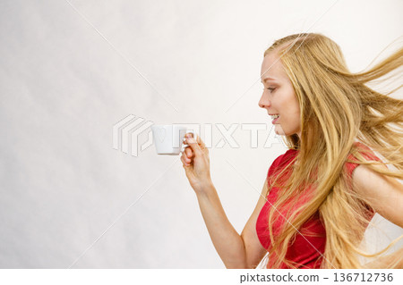 Blonde girl blowing hair holds coffee cup Blonde girl blowing hair holds coffee cup 136712736