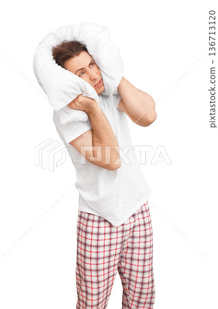 Annoyed man in pajamas covering his head with a white pillow to block noise, isolated on white background. Concept of insomnia, stress, headache, or loud neighbors preventing sleep. High quality photo Annoyed man in pajamas covering his head with a white pillow to block noise, isolated on white background. Concept of insomnia, stress, headache, or loud neighbors preventing sleep. High quality photo 136713120
