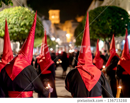 Many nazarenos with red hoods walking in procession 136713288