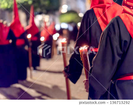 Many nazarenos with red hoods walking in procession 136713292