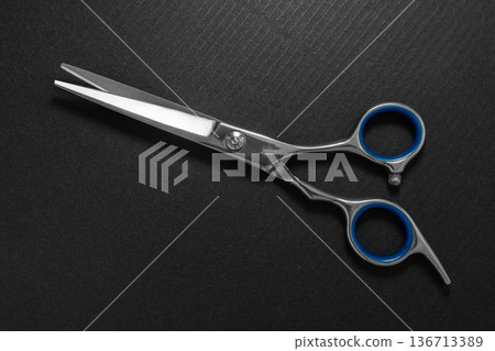 Close-up of hairdressing scissors on a black 136713389