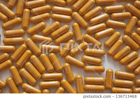 Minimal top-down flatlay with bright curcumin capsules scattered on white marble, highlighting vibrant wellness aesthetics and clean modern style Minimal top-down flatlay with bright curcumin capsules scattered on white marble, highlighting vibrant wellness aesthetics and clean modern style 136713468