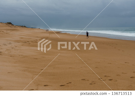Runner on the beach in Labenne, Landes, France, under a cloudy sky. Runner on the beach in Labenne, Landes, France, under a cloudy sky. 136713513