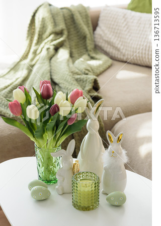 Living Room Decorated Easter Eggs with Bunny Figurines, Candles and Tulips. Cozy Spring Holiday Arrangement Living Room Decorated Easter Eggs with Bunny Figurines, Candles and Tulips. Cozy Spring Holiday Arrangement 136713595