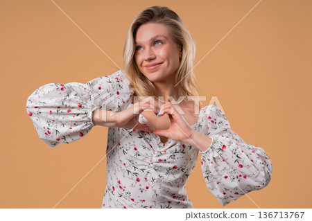 Smiling Charming Woman Showing Sign Of Shape Heart. Romantic Woman On Beige Smiling Charming Woman Showing Sign Of Shape Heart. Romantic Woman On Beige 136713767