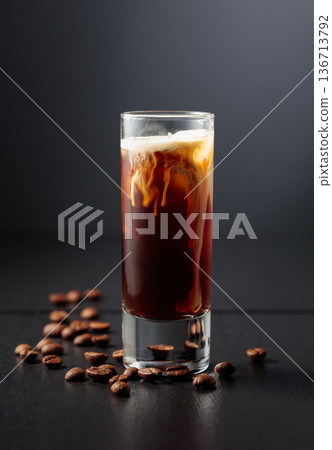 Cream and coffee liquor with ice in tall glass on a black background. Cream and coffee liquor with ice in tall glass on a black background. 136713792