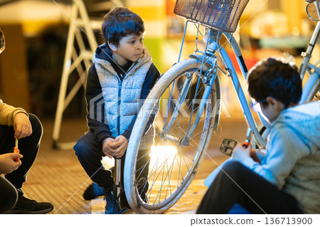 Young boy learning bicycle repair skills with friends 136713900