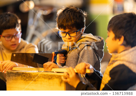 Young boys learning woodworking skills with hand saws 136713988
