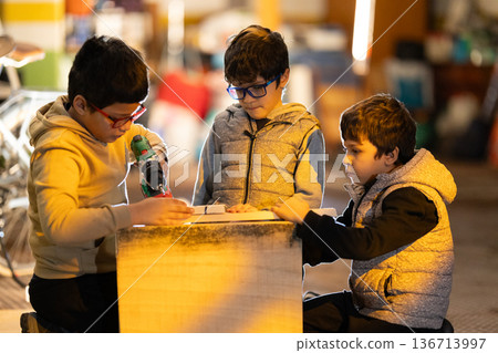 Boys learning woodworking skills using power tools 136713997