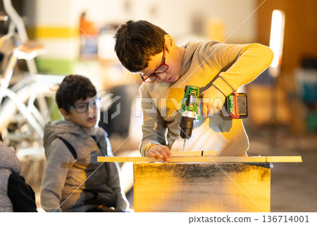 Child developing practical skills using power drill 136714001