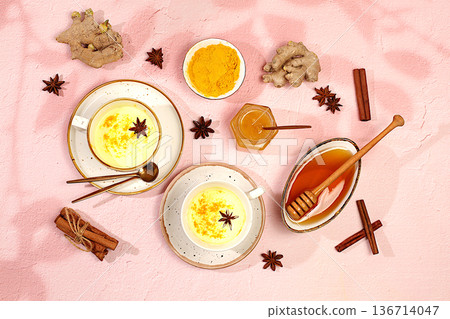 Golden turmeric latte with ginger, cinnamon, anise and honey spices on sunny table. Weight loss and alternative medicine concept, immunity booster during pandemic, Indian cuisine advertisement. 136714047
