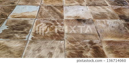 A rug made of square cowhide leather patches in shades of brown and beige. Concept: natural materials, eco-friendly decor, country style, textured background, rustic interior design A rug made of square cowhide leather patches in shades of brown and beige. Concept: natural materials, eco-friendly decor, country style, textured background, rustic interior design 136714060