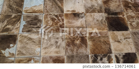A rug made of square cowhide leather patches in shades of brown and beige. Concept: natural materials, eco-friendly decor, country style, textured background, rustic interior design A rug made of square cowhide leather patches in shades of brown and beige. Concept: natural materials, eco-friendly decor, country style, textured background, rustic interior design 136714061