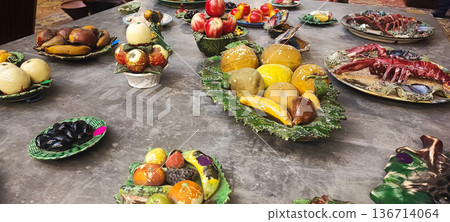 Handicrafts ceramic fruits, vegetables, seafood, and breads displayed on decorative plates and platters. Concept: traditional markets, handicrafts, interior design, artisan craftsmanship. Handicrafts ceramic fruits, vegetables, seafood, and breads displayed on decorative plates and platters. Concept: traditional markets, handicrafts, interior design, artisan craftsmanship. 136714064