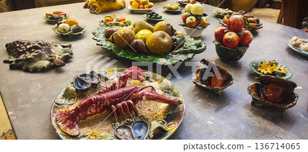 Handicrafts ceramic fruits, vegetables, seafood, and breads displayed on decorative plates and platters. Concept: traditional markets, handicrafts, interior design, artisan craftsmanship. 136714065