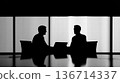 Silhouette Of Two Businessmen In Meeting Across A Table With Laptop In Modern Office 136714337