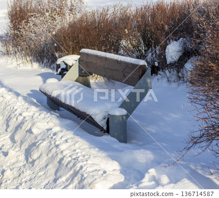 A park bench covered in snow during winter A park bench covered in snow during winter 136714587