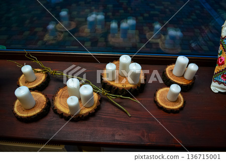 White candles on wooden slices by window 136715001