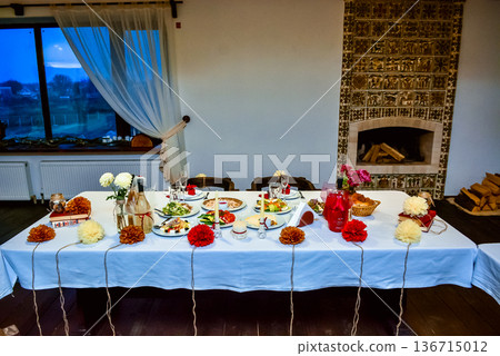 Festive dinner table set in a rustic room with fireplace Festive dinner table set in a rustic room with fireplace 136715012