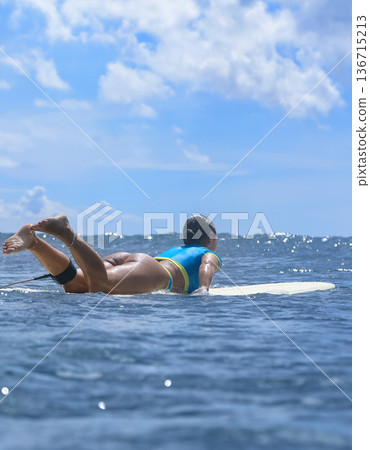 Athletic female surfer Amidst Scattered Clouds From Ocean Perspective Athletic female surfer Amidst Scattered Clouds From Ocean Perspective 136715213