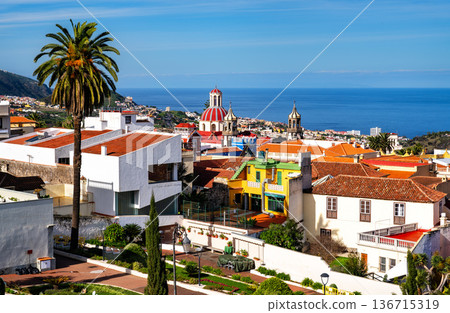 View of the historic town of La Orotava and the Church of La Concepcion in Tenerife, Canary Islands, Spain. Features colorful houses, palm trees, and the Atlantic Ocean. View of the historic town of La Orotava and the Church of La Concepcion in Tenerife, Canary Islands, Spain. Features colorful houses, palm trees, and the Atlantic Ocean. 136715319
