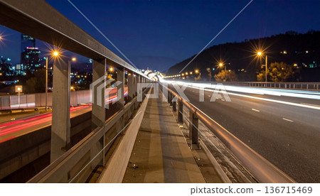 夜晚，從人行天橋上拍攝的第一人稱視角鏡頭，俯瞰下方城市道路上行駛的車輛留下的紅白燈光軌跡。 136715469