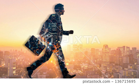 Silhouette of a businessman walking to work, overlapping with the city sparkling in the evening sky 136715695