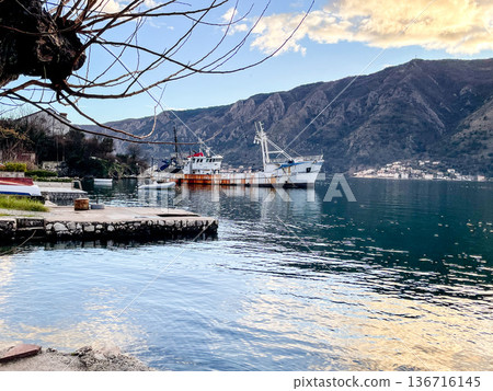 Serene maritime craft berthed along industrial shoreline scene 136716145