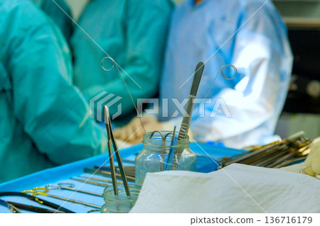 Surgeons prep for surgery with key tools on tray team members focused an operating room background. 136716179