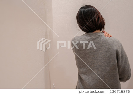 A woman with stiff shoulders putting her hands on her shoulders 136716876