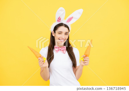 Funny woman with bunny ears celebrate easter on yellow studio background. Bunny girl face. Woman in easter rabbit mask. Funny woman with bunny ears celebrate easter on yellow studio background. Bunny girl face. Woman in easter rabbit mask. 136718945
