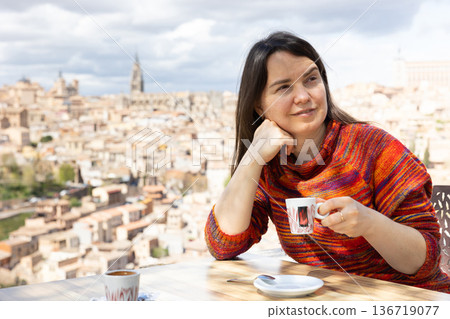 Portrait of female tourist drinking coffee at table overlooking Toledo, Mirador del Valle, Spain Portrait of female tourist drinking coffee at table overlooking Toledo, Mirador del Valle, Spain 136719077