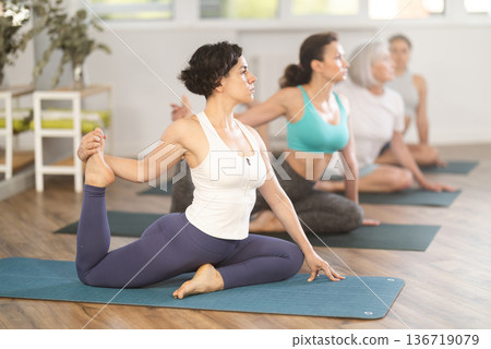 Woman performing Eka Pada Kapotasana during group yoga session 136719079