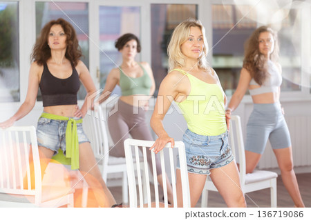 Putting foot hand on seat of chair, girl improvises, perform lap dance during group master class Putting foot hand on seat of chair, girl improvises, perform lap dance during group master class 136719086
