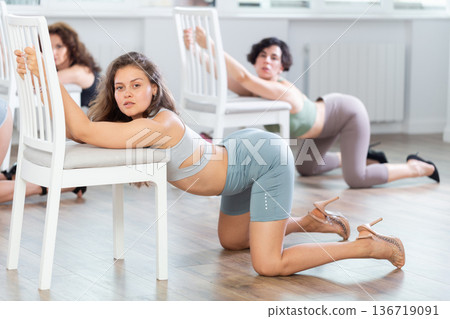 Group of women in high heels rehearsing dance while kneeling on floor Group of women in high heels rehearsing dance while kneeling on floor 136719091