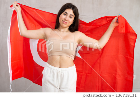 Happy young woman with flag of Turkey against unicoloured background 136719131
