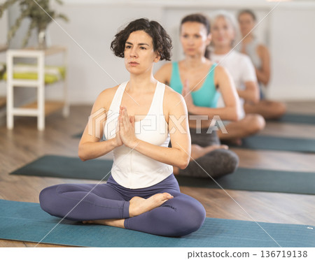 Hispanic woman meditating in Padmasana during group yoga class 136719138