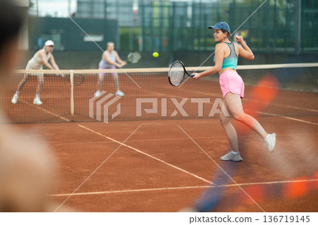 Emotional fit young girl playing doubles tennis on outdoor court 136719145
